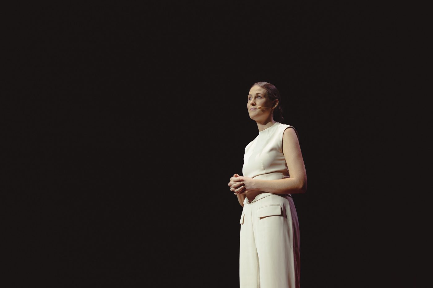 Hailey Brown stands on stage in a white blouse and trousers