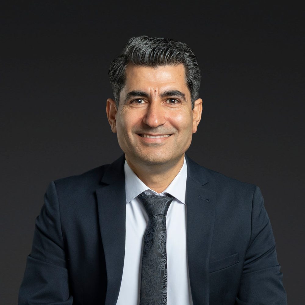 Headshot of Abbas Shafiee smiling against a dark background.