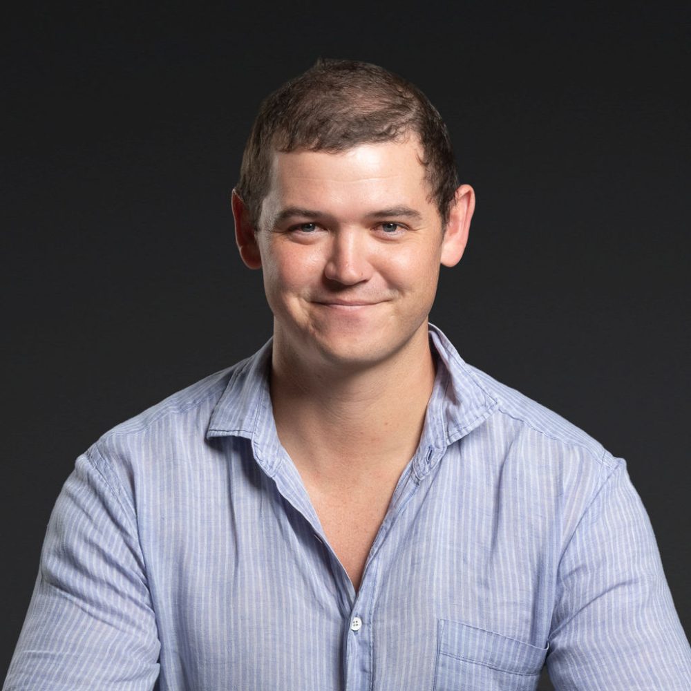 Headshot of Bill Ovenden smiling against a dark background.