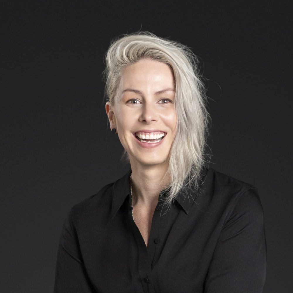 Headshot of Nicole Dyson smiling against a dark background.